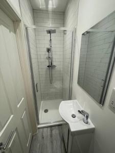 a white bathroom with a shower and a sink at Stunning Central Woking Studio in Woking