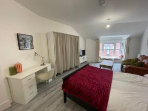 a bedroom with a bed and a desk with a red blanket at Stunning Central Woking Studio in Woking