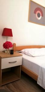 a bedroom with a bed and a table with a lamp at Apartman Hana in Donji Štoj