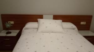 a bed with two pillows on it in a bedroom at Casa de verano in O Grove