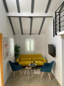 sala de estar con sofá amarillo y 2 sillas azules en GALLERY, en Nerezine