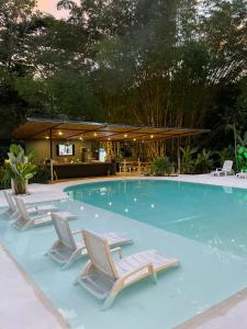 a swimming pool with lounge chairs and a table at Grand Park Manuel Antonio - Adults Only in Manuel Antonio