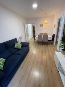a living room with a blue couch and a dining room at Apartamento en la costa del Maresme in Pineda de Mar