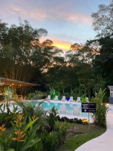 a resort pool with chairs and a sunset at Grand Park Manuel Antonio - Adults Only in Manuel Antonio