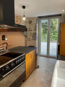 cocina con fogones horno superior junto a una ventana en Le Val Éveillé - maison de maître de 1773 - 4* en Arudy