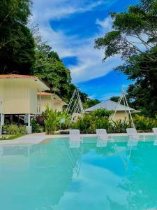 a swimming pool with two chairs in front of a house at Grand Park Manuel Antonio - Adults Only in Manuel Antonio