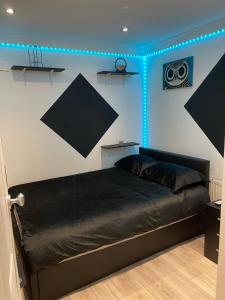 a bedroom with a bed with black sheets and blue lights at Modern Appartment in London