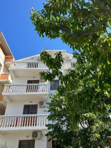 a white building with balconies and a tree at Apartments Hotel AL&DE in Velipojë