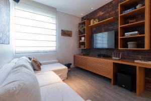 a living room with a couch and a television at Apto. espaçoso com workspace -por Casapē in Rio de Janeiro