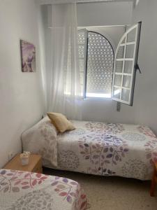 - une chambre avec 2 lits et une fenêtre dans l'établissement PISO ATuN, à Barbate