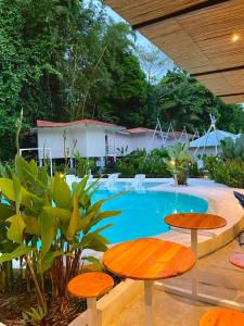 a swimming pool with two tables and chairs next to it at Grand Park Manuel Antonio - Adults Only in Manuel Antonio