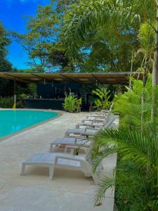 a row of lounge chairs next to a swimming pool at Grand Park Manuel Antonio - Adults Only in Manuel Antonio