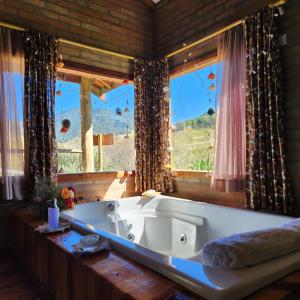 bañera grande en una habitación con ventanas en Pousada Vale Monte Azul, en Santo Antônio do Pinhal
