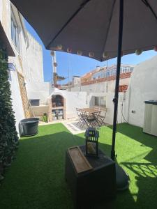 un patio con sombrilla y césped verde en Beato Typical House, en Lisboa