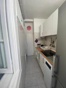 una pequeña cocina con armarios blancos y fregadero en Beato Typical House en Lisboa