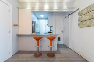 a kitchen with two orange stools in front of a counter at Apto. espaçoso com workspace -por Casapē in Rio de Janeiro