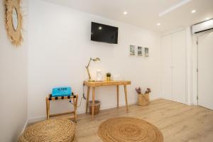 uma sala de estar com uma mesa e uma televisão na parede em CASA BRISA, MAR E SOL SESIMBRA em Sesimbra