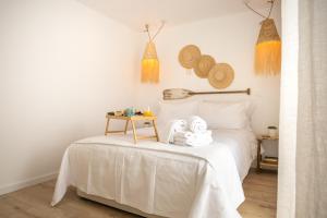 a bedroom with a bed with white sheets and a table at CASA BRISA, MAR E SOL SESIMBRA in Sesimbra