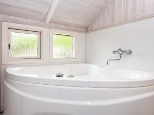 uma casa de banho branca com uma banheira e uma janela em 5 person holiday home in B rkop em Egeskov