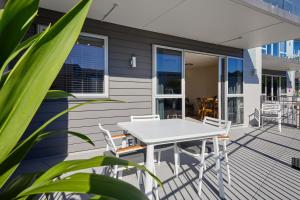 um deque com uma mesa branca e cadeiras numa casa em Kaikoura Waterfront Apartments em Kaikoura