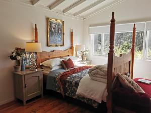 a bedroom with a bed with a wooden frame and two windows at Wyndover Mountain Retreat in Beechmont
