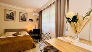 a bedroom with a bed and a table with a vase of flowers at LE MIRAMAR Nice - Clim, Parking, Wifi et piscine in Nice +8 photos