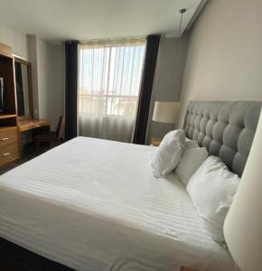 a large white bed in a bedroom with a window at Suites Del Ángel in Mexico City