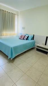 una camera da letto con letto con lenzuola e cuscini blu di Apartamento Thermas a Caldas Novas