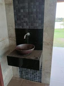 a bathroom sink with a bowl on a tiled wall at Casa no Condomínio Naútico Porto da Pedra em Ijaci in Macaia