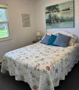 a bedroom with a bed with a floral comforter at Little Haven Cottage an ocean view 2 bedroom cottage in Savage Harbour in Mount Stewart