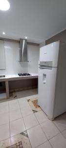 Il comprend une cuisine équipée d'un réfrigérateur blanc et d'un comptoir. dans l'établissement Macuco Departamentos, à Puerto Iguazú