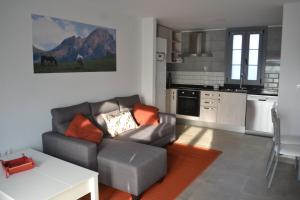 een woonkamer met een bank en een keuken bij El Molino 3 in Muros de Nalón