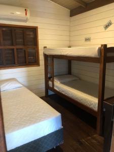 two bunk beds in a room with wooden walls at Pousada Aloha Beach House in Praia do Rosa