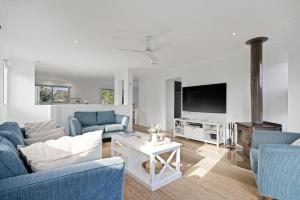 uma sala de estar com mobiliário azul e uma televisão de ecrã plano em Island Court em Smiths Beach