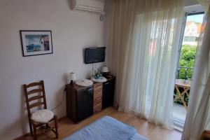 a bedroom with a tv and a chair and a window at Triple Room Supetar 5658b in Supetar