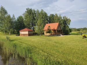 a house in the middle of a field with a lake at Wypoczynek nad stawami in Sobiechy