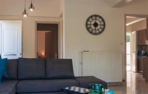 a living room with a couch and a clock on the wall at Archontissa Kakodiki - Paleochora in Palaiochora +36 photos