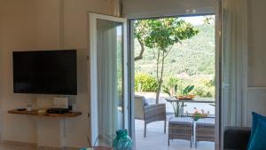 a living room with a television and a sliding glass door at Archontissa Kakodiki - Paleochora in Palaiochora