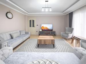 ein Wohnzimmer mit einem Sofa und einem TV in der Unterkunft Grand Crown Suites - شقق غراند كراون السياحية in Trabzon