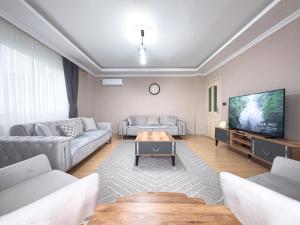 ein Wohnzimmer mit einem Sofa und einem TV in der Unterkunft Grand Crown Suites - شقق غراند كراون السياحية in Trabzon