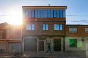 a man walks in front of a brick building at The Little House ApartHotel in Uyuni