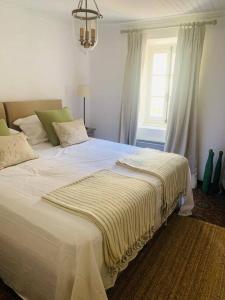 ein großes weißes Bett in einem Zimmer mit Fenster in der Unterkunft Beautiful South of France Home with Pool in Gabian