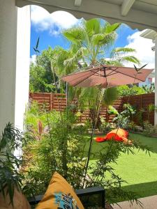 a patio with a pink umbrella and a garden at Wave Coconut Villa in Le Moule