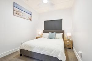 Habitación blanca con cama y mesita de noche en Seaside Serenity Modern Cottage with Spa, en Machans Beach