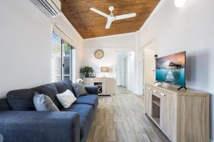 sala de estar con sofá azul y TV en Seaside Serenity Modern Cottage with Spa, en Machans Beach