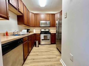 una cocina con armarios de madera y electrodomésticos de acero inoxidable en UPSCALE Condo Near NYC, MetLife & American Dream, en Passaic