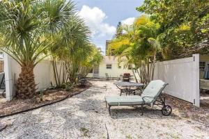 a patio with a chair and a table and palm trees at Lovely 1 Bedroom Unit Across from Lido Key Beach in Sarasota