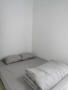 a white room with a bed with two pillows at Rumah Kembar DI kawasan wisata lembang in Citeureup 1