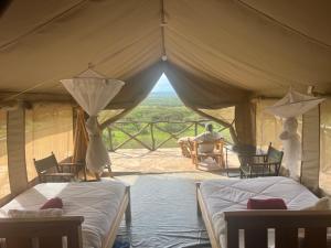 ein Zelt mit 2 Betten und ein Mann am Tisch in der Unterkunft Sunset camp in Narok