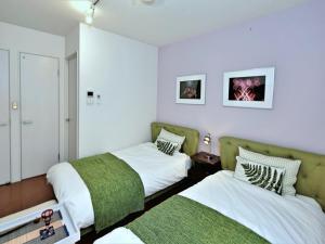 2 łóżka w pokoju z białymi ścianami w obiekcie Numero Uno Tokyo w Tokio